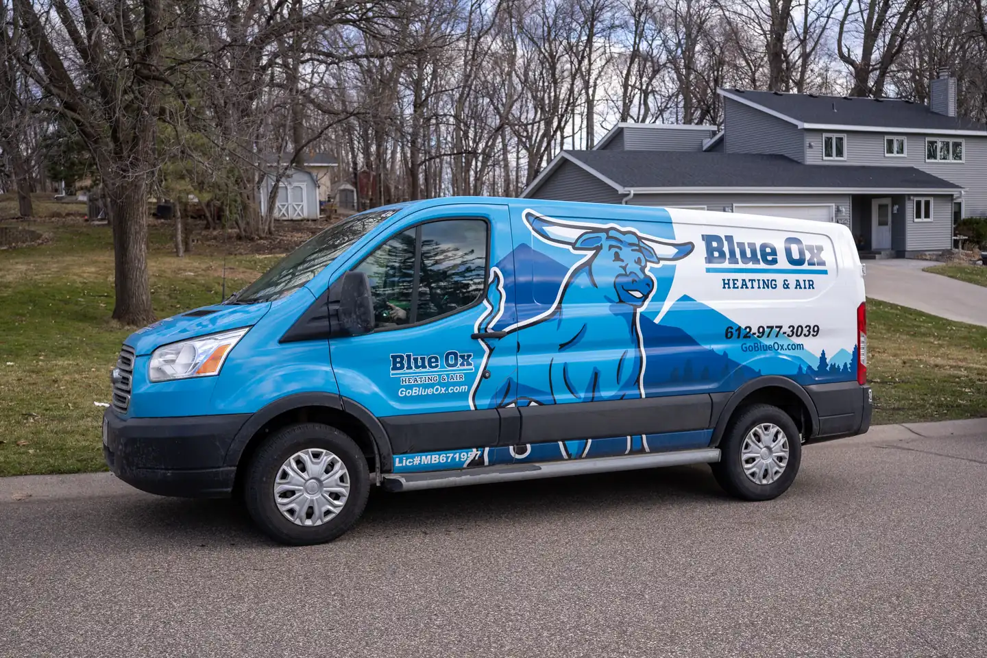Blue and white Blue Ox Heating & Air van parked on a residential street.